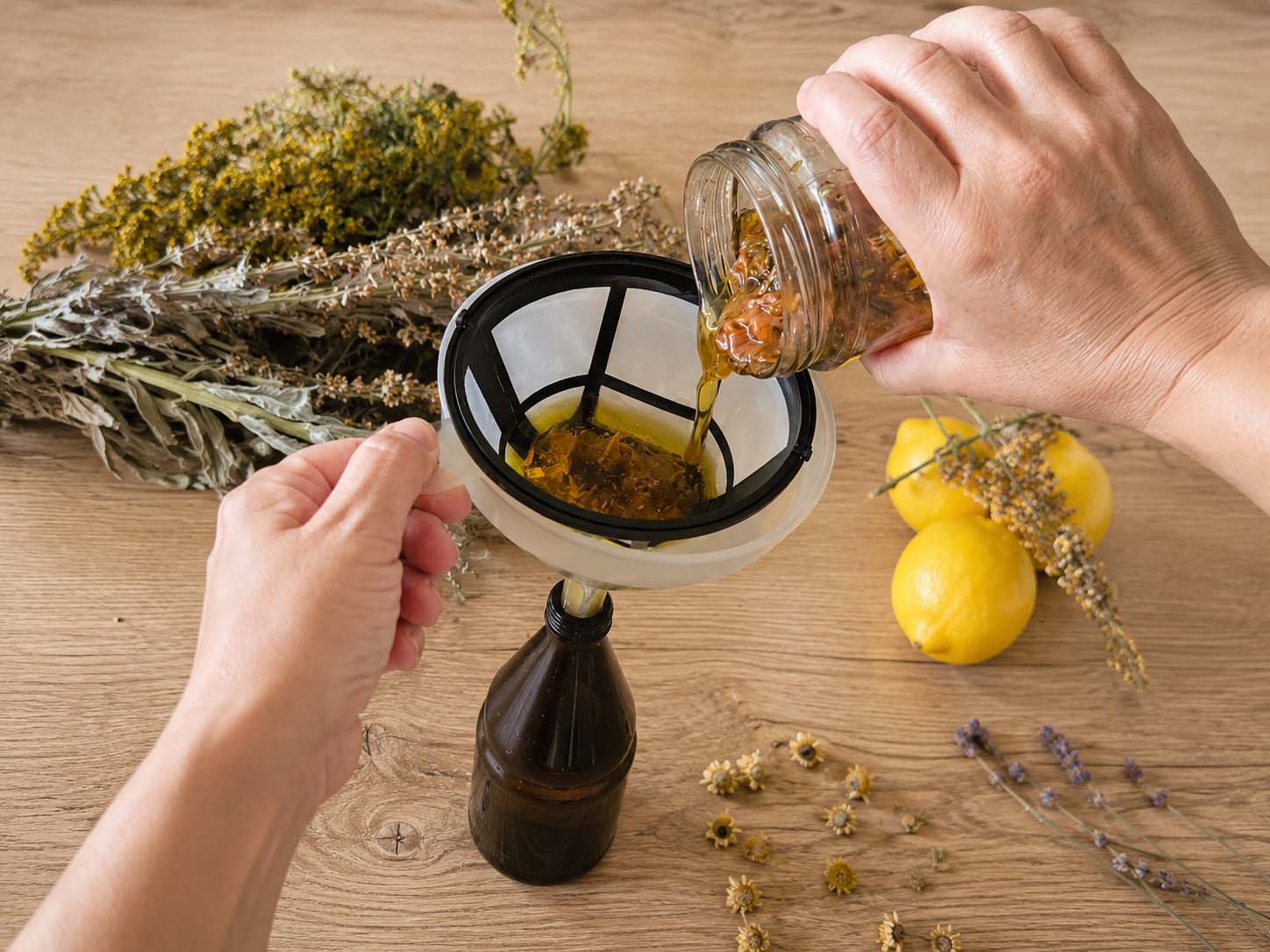 Manos filtrando un oleato botánico artesanal
